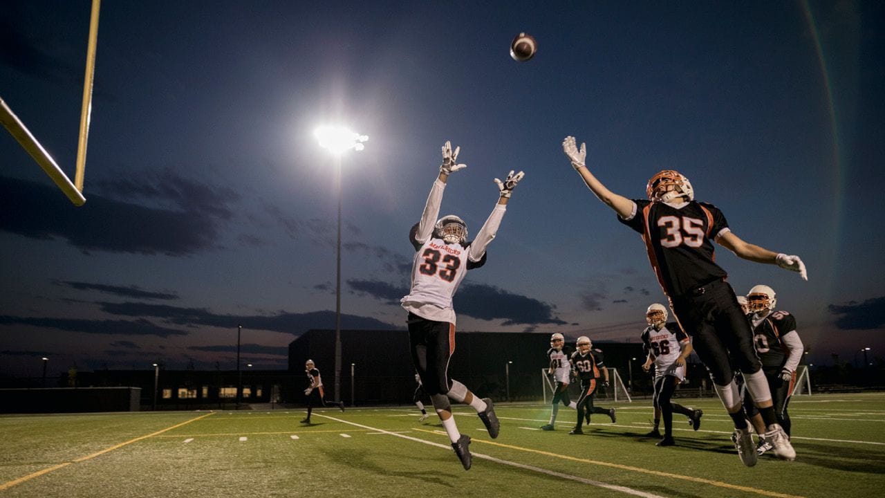Youth football players reaching for a pass on the field