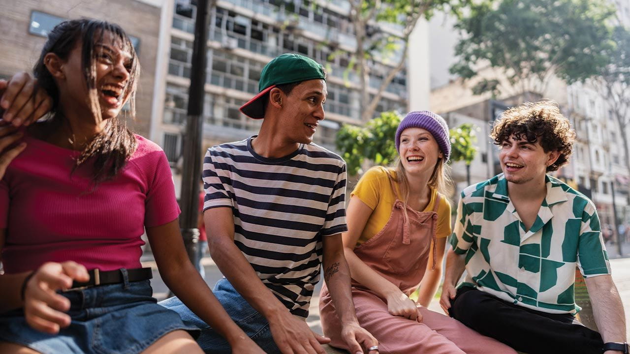 A group of teens and young adults sitting together outdoors in the city.