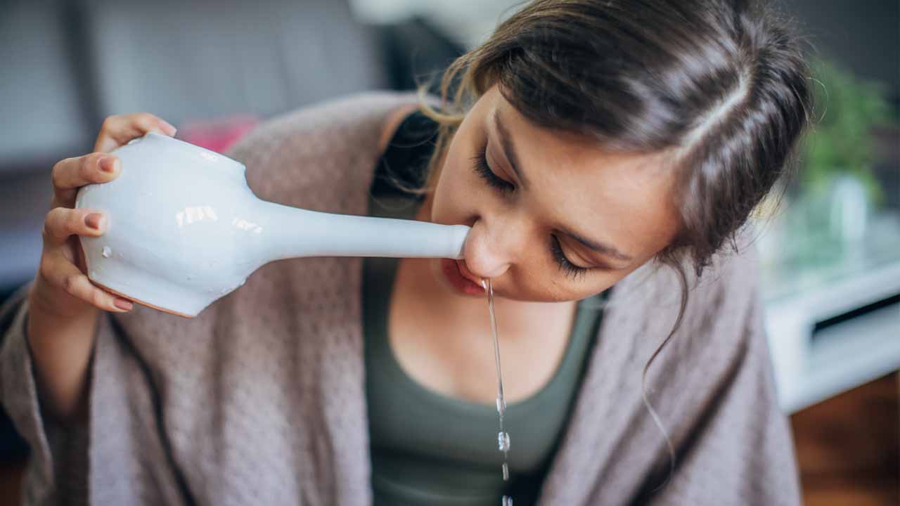 A woman uses a neti pot to rinse her nasal passages