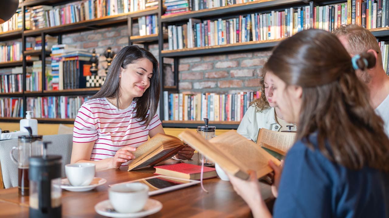 A book club discusses a book together in a library.
