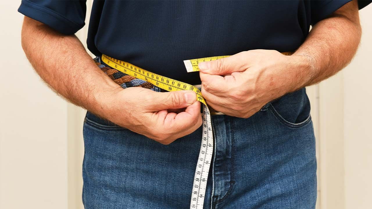 Person measuring their waist with a yellow measuring tape