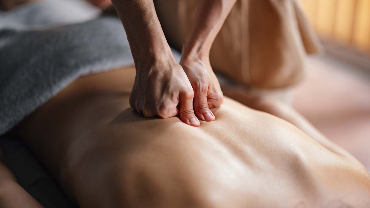 Massage therapist applying pressure to a person’s back.