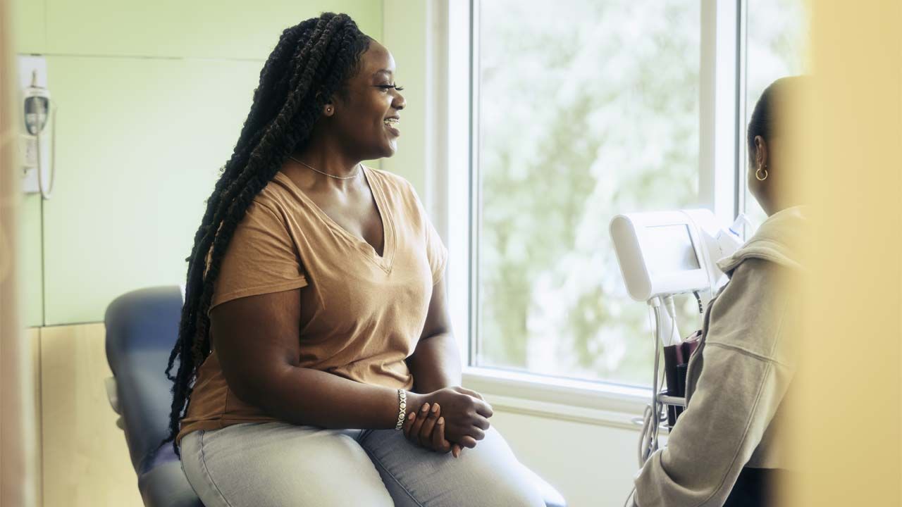 A woman talks to her doctor about her risk for polyendocrine metabolic ovarian syndrome, or PMOS.