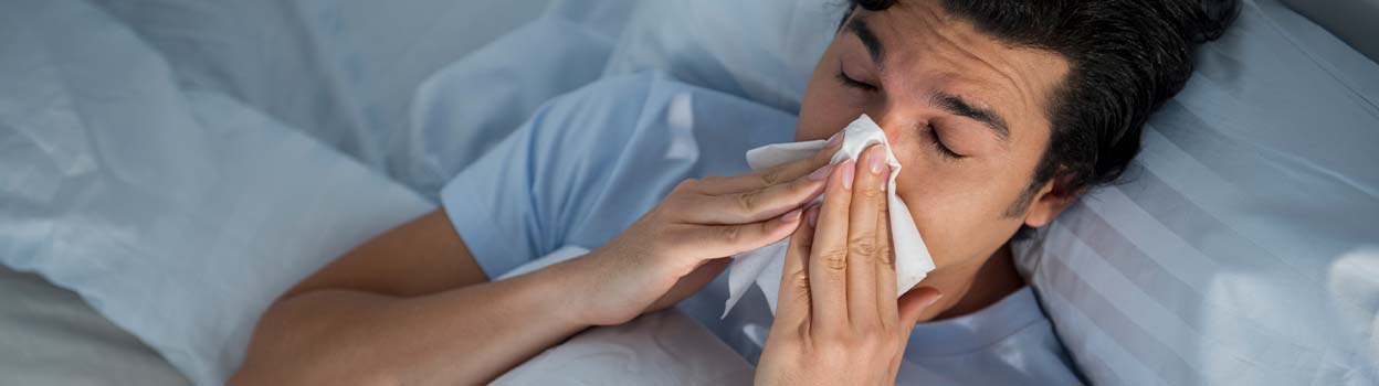man sneezing in bed