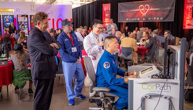 Alan Lumsden, Thomas Loh, and C Huie Lin watch astronaut Kjell Lindgren operate a surgical robot.