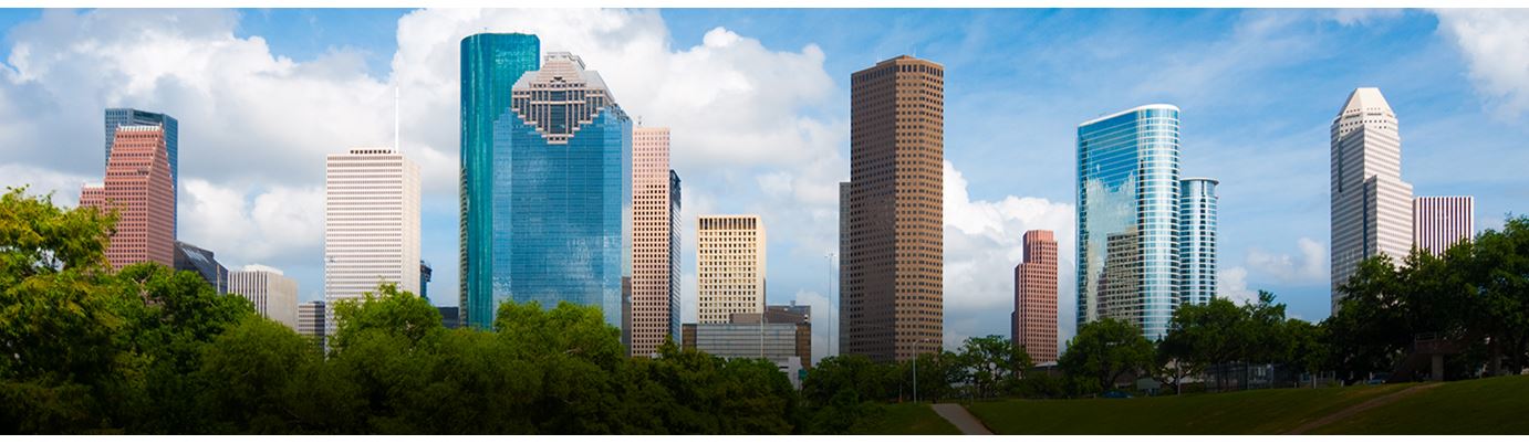 Downtown Houston skyline with tall buildings, blue sky and fluffy clouds