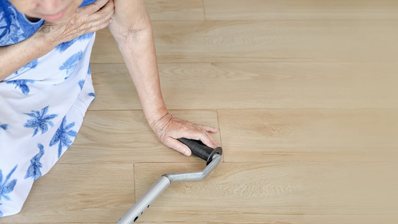 Person seated on a floor with cane after fall.