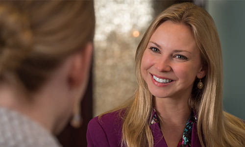 woman facing camera, smiling and conversing with global staff