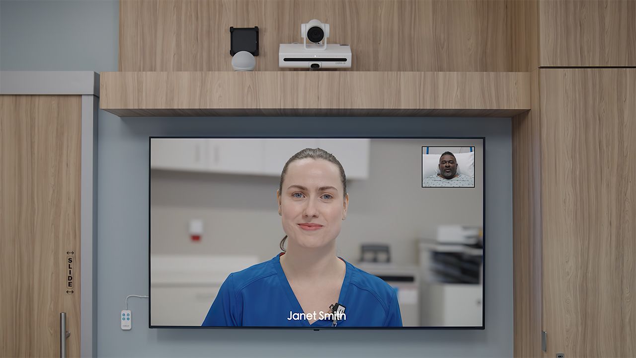 A virtual nurse appears on the screen in a patient room
