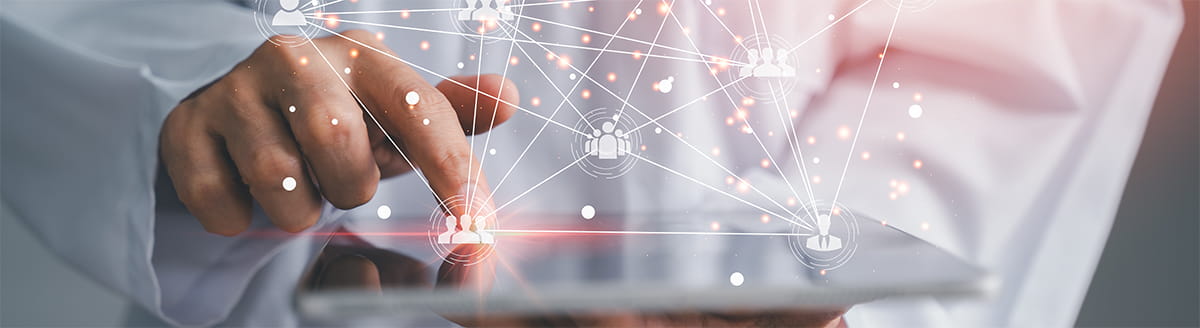 Close-up of a doctor's hand interacting with a tablet screen overlaid with a digital network graphic. Connected user icons, lines, and glowing nodes spread across the image, illustrating digital connectivity, data sharing, collaboration, or healthcare access transformation.