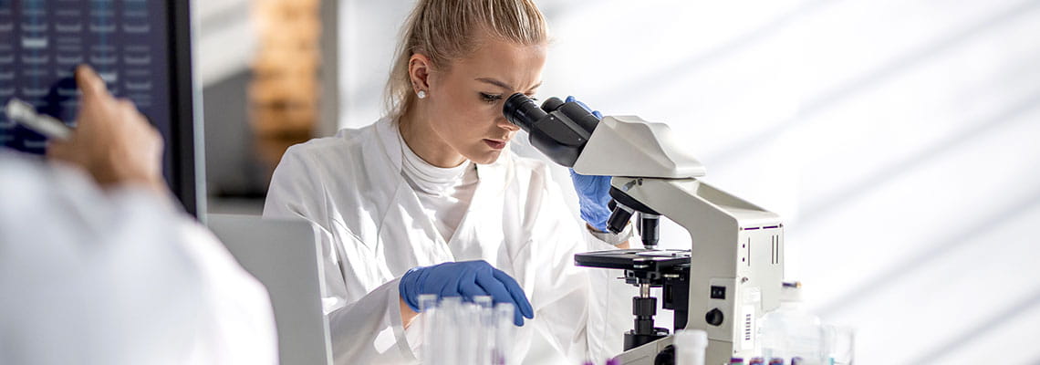 Medical researcher looking through microscope