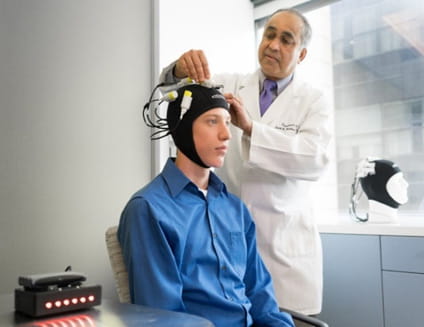 Dr Helekar placing magnetic stimulation device on patients head