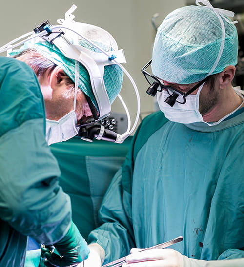 Close-up of surgeons performing a cardiovascular surgical procedure in an operating room using specialized surgical equipment and protective attire.