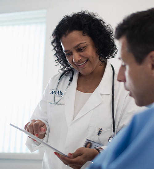 Houston Methodist healthcare provider reviewing treatment information on a tablet with a patient during a cardiovascular care consultation.