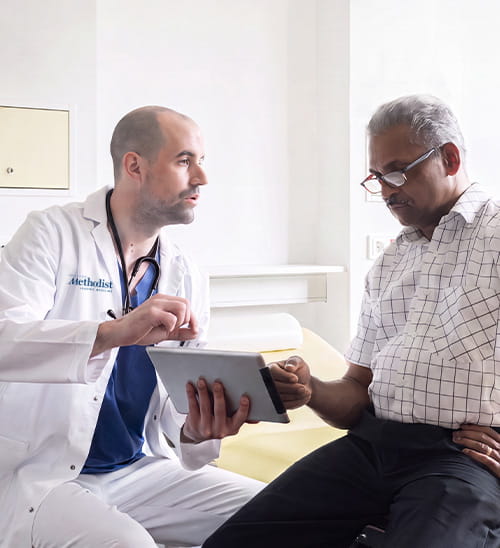 Healthcare provider and patient reviewing information on a tablet during an office visit.