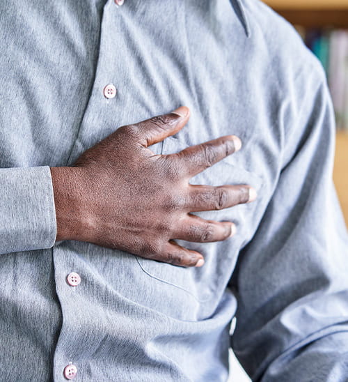 Close-up of a person with a hand placed on the chest, representing chest pain, chest discomfort, or another symptom that may require medical evaluation.