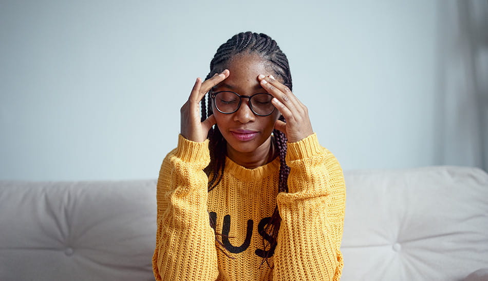 Woman holding her head with both hands, appearing stressed or in pain.