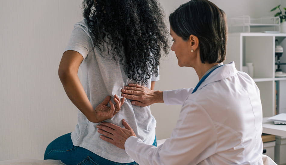 Healthcare provider assessing a patient’s back for pain or injury.
