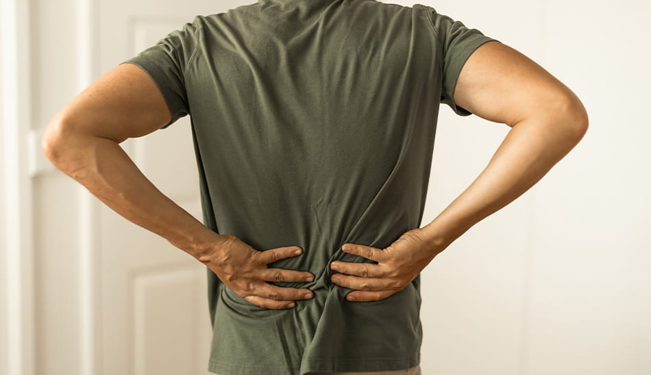 Man from behind holding his lower back in pain