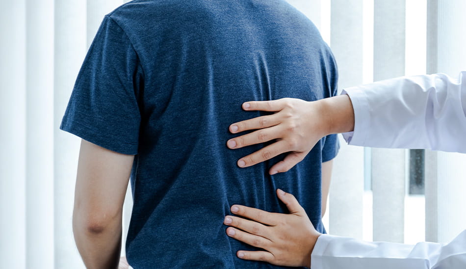 Doctor examining a patient’s back during a medical checkup.
