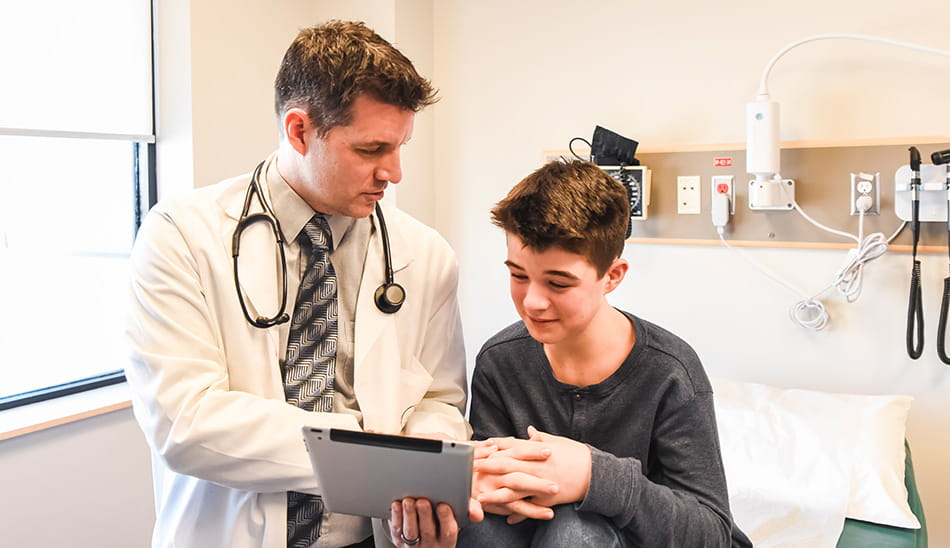 Doctor and young patient looking at medical information together on a tablet device.