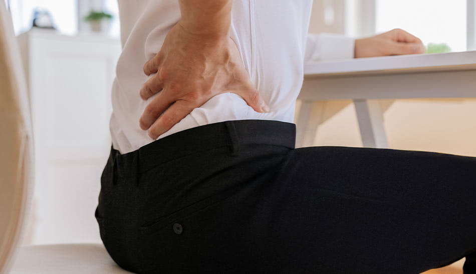 Side view of a person holding their lower back in pain.