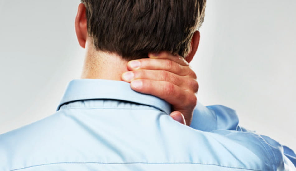 Man seen from behind holding his neck, suggesting pain or discomfort.