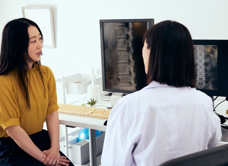 Spine specialist showing a patient an X-ray of their back during a consultation.