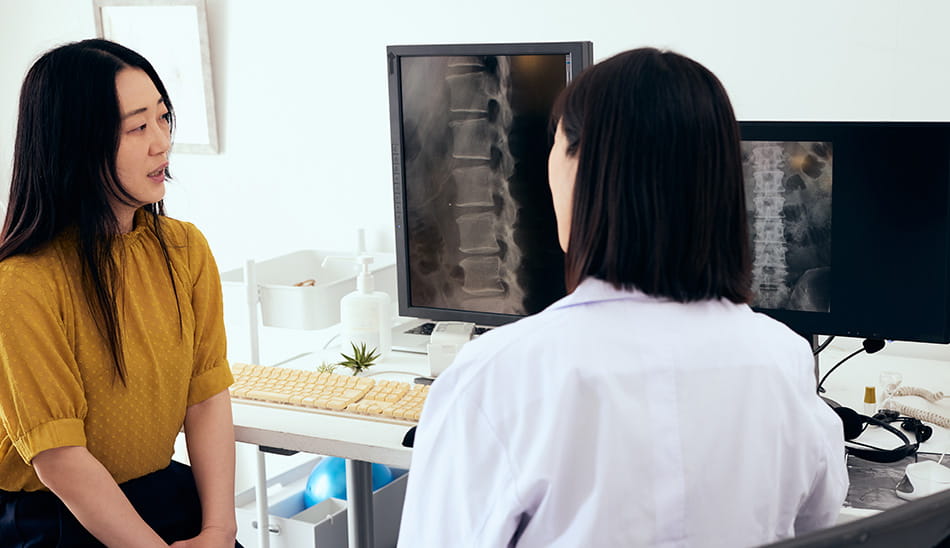 Spine specialist showing a patient an X-ray of their back during a consultation.