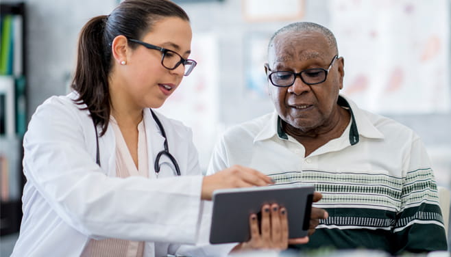 Doctor sitting with a patient and referencing to screen on digital pad