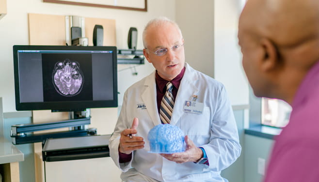doctor holding brain model explaining to patient about condition and treatment
