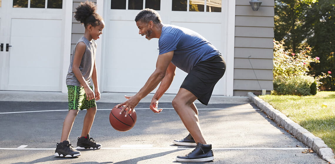 father and daughter playing basket ball bending knees